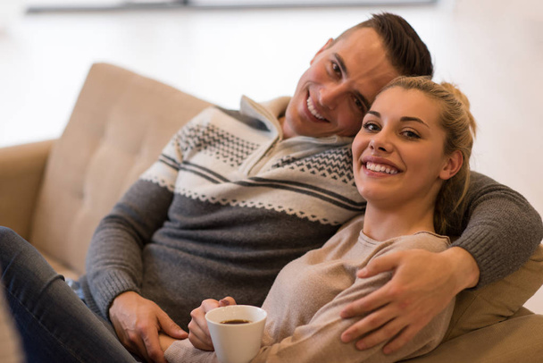 Young romantic couple sitting on sofa - Foto, afbeelding