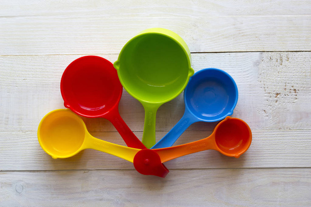 Colorful measuring spoons for kitchen on a white wooden backgrou - Zdjęcie, obraz