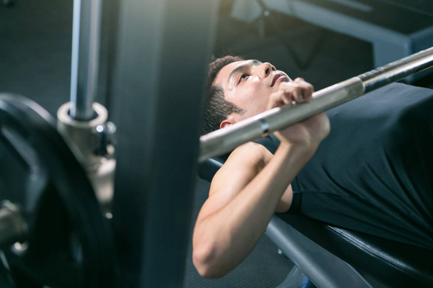 Homme soulevant haltères poids tout en étant couché dans la salle de gym
. - Photo, image