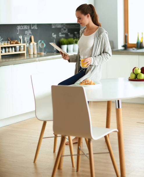 Junge Frau mit Orangensaft und Tablette in Küche - Foto, Bild