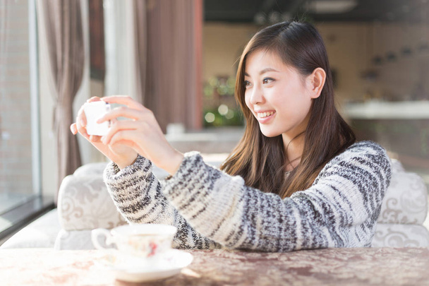 Kiinalainen nainen kanssa matkapuhelin kahvilassa
 - Valokuva, kuva