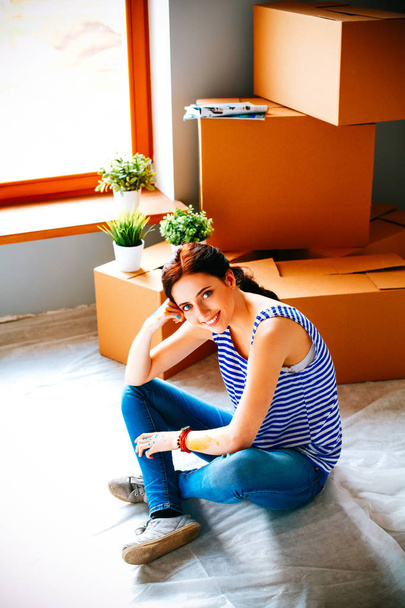Woman in a new home with cardboard boxes - 写真・画像