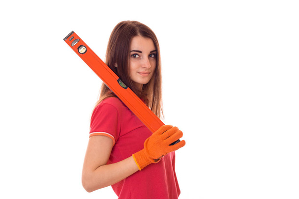 beautiful girl in a red shirt stands sideways and holding a device for measuring the level of isolated on white background - Photo, image