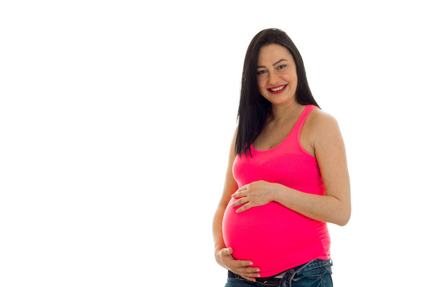 young pregnant brunette girl touching her belly isolated on white background - Photo, image