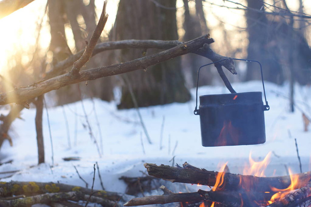 Ein Topf mit kochendem Wasser auf dem Feuer wärmt im Winterwald, - Foto, Bild