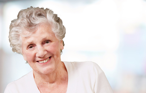 Portret van senior vrouw die lacht over abstracte achtergrond - Foto, afbeelding