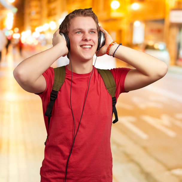 portrait of cheerful young student listening music with headphon - Photo, image