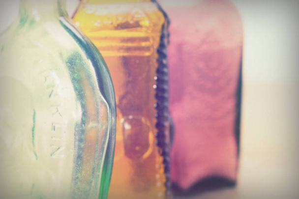Bottiglie di vetro colorato su sfondo rustico
 - Foto, immagini