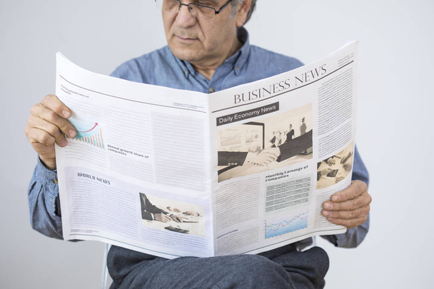 Ανώτερος άνθρωπος διαβάζοντας εφημερίδα σε γκρίζο φόντο - Φωτογραφία, εικόνα