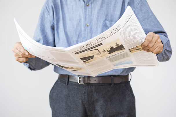 Чоловік тримає читання газети на сірому фоні
 - Фото, зображення