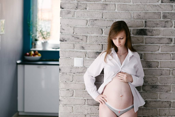 Hamile kadın gri tuğla duvar tarafından poz - Fotoğraf, Görsel