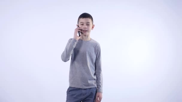 kleine jongen met een telefoontje geïsoleerd op witte achtergrond - Video