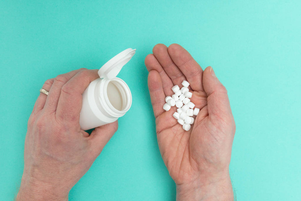 Mains tenant une bouteille de médicament et des pilules blanches
 - Photo, image