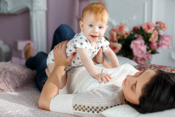 Happy mother playing with baby boy lying on bed at home - Foto, Imagem