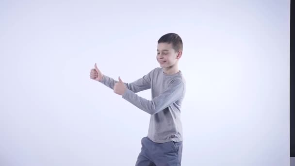 smiling boy holding his thumb up isolated on the white background - Filmagem, Vídeo