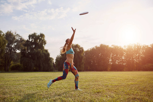 Молодая спортсменка играет с летающим диском, конечная
 - Фото, изображение