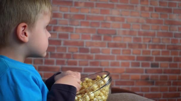 Мальчик сидит с попкорном на диване и смотрит кино
 - Кадры, видео