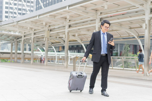 Young asian businessman using smartphone while walking outside b - Φωτογραφία, εικόνα