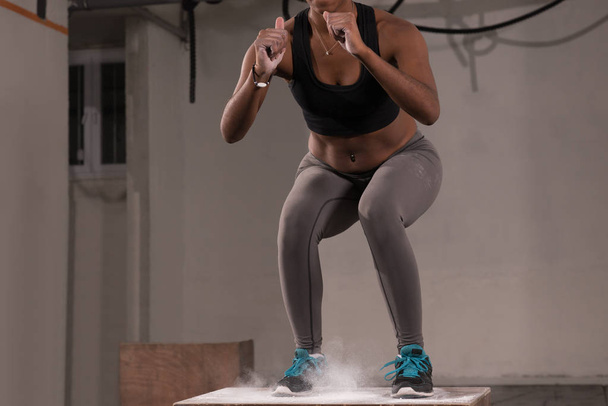 black woman is performing box jumps at gym - Фото, зображення