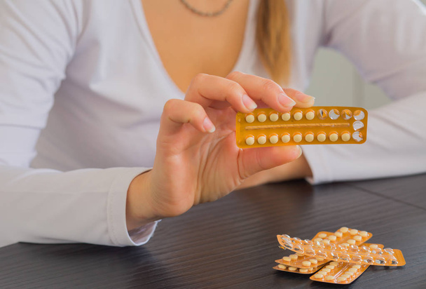 Woman holding pack of contraceptive pills and glass of water. - Photo, Image