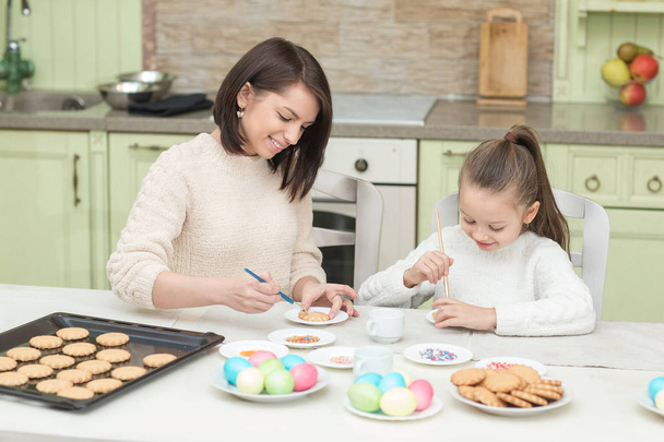 Mom and her daughter baking together and decorating the cookies - Foto, Imagem