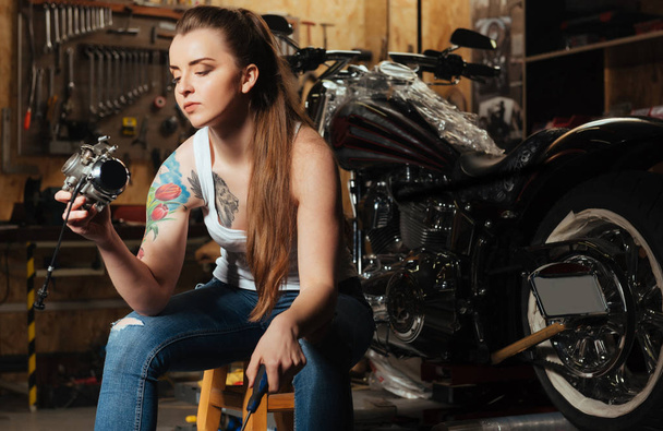 Serious female biker keeping screwdriver in left hand - Фото, изображение
