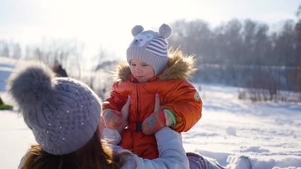 Girl plays with baby at sunny in winter time. Holding on hands - Footage, Video