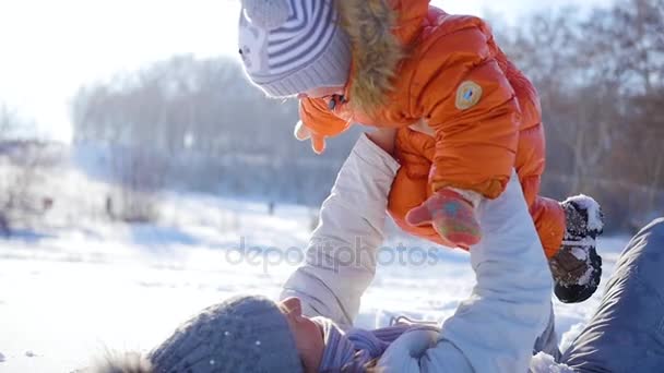 Κορίτσι παίζει με το μωρό στο ηλιόλουστο χειμώνα. Κρατώντας στα χέρια - Πλάνα, βίντεο