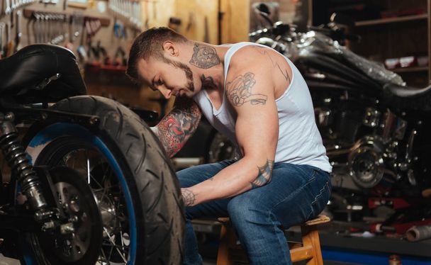 Serious man repairing his motorbike - Zdjęcie, obraz