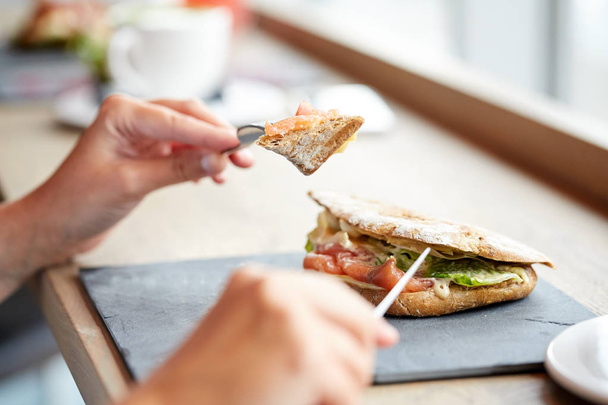 woman eating salmon panini sandwich at restaurant - Valokuva, kuva