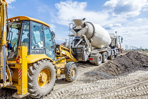 LKW-Mischer gießt Beton in Bulldozer-Schaufel - Foto, Bild