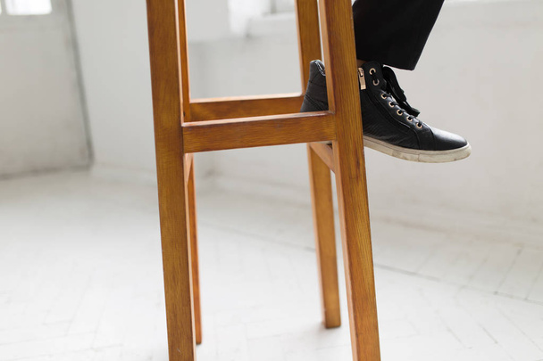 Laconic style - woman in gumshoes sitting on a wooden stool - Φωτογραφία, εικόνα