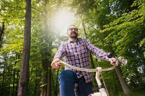 Young modern man riding bike in park - Фото, зображення