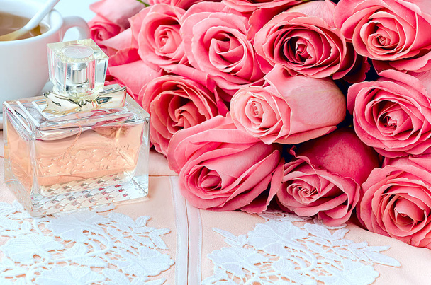Μπουκάλι άρωμα, κεντημένα φούστα σχεδιαστών, φλιτζάνι τσάι και μάτσο τριαντάφυλλα - Φωτογραφία, εικόνα