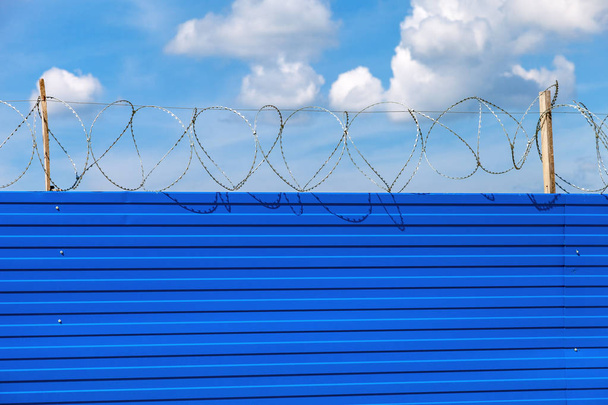 Barbed wire on the fence against a blue sky background. Restrict - Photo, Image