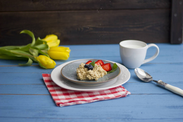 Porridge with berries, fresh strawberries and blueberries. Strewing with powdered sugar - Foto, imagen