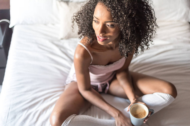 woman reading a book and drinking coffee on bed with socks - Foto, Imagem