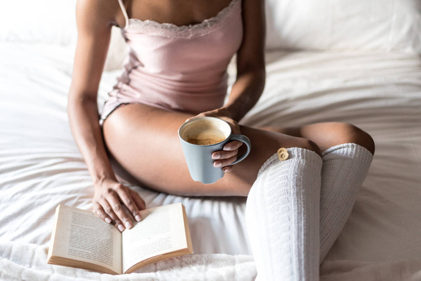 Kobieta z książką i picie kawy na łóżku z skarpety - Zdjęcie, obraz