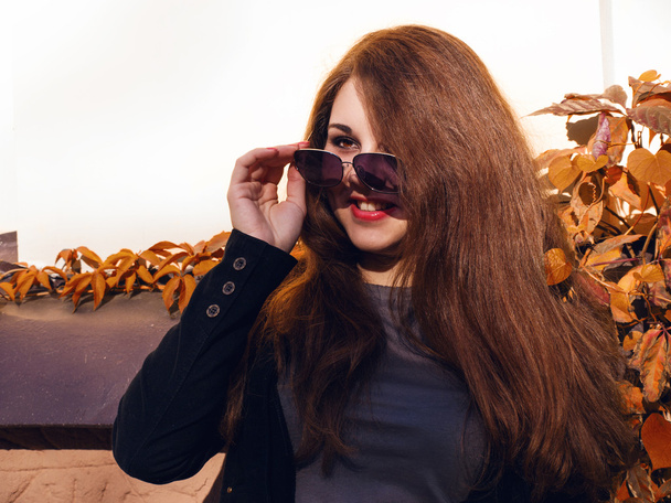 Girl with red hair and sunglasses smiling - Фото, зображення