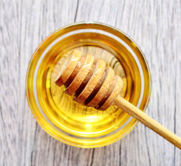 Golden honey with honey stick on a wooden table - Photo, Image