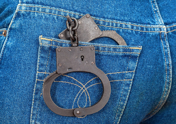 Black metal handcuffs in back jeans pocket - Photo, Image
