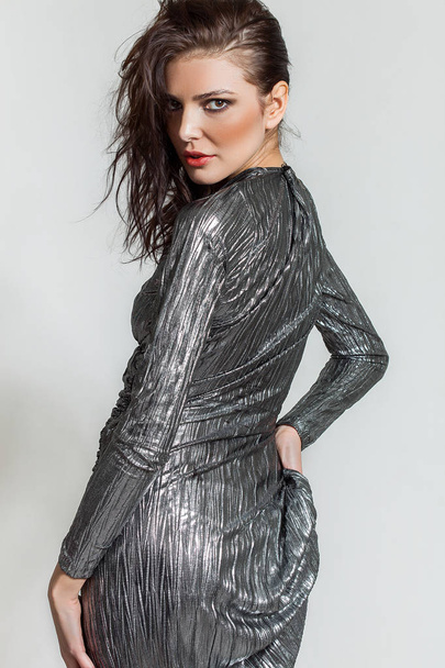 Beautiful woman portrait turning and looking while wearing silver dress - Foto, Imagem