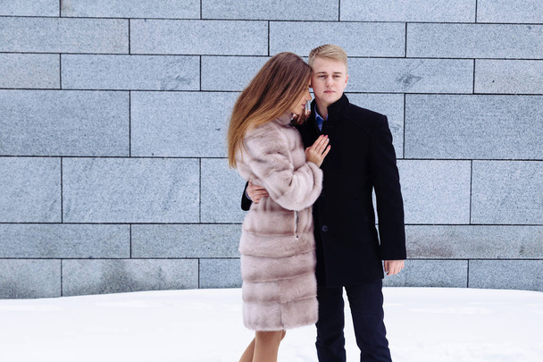 Mladý heterosexuální muž a žena v páru kabát kožešina obejmout a políbit navzájem šťastný v městě. - Fotografie, Obrázek