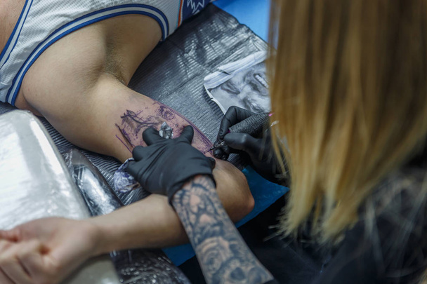 Een tatoeëerder is het ontwerpen van een tattoo op de arm van een client - Foto, afbeelding