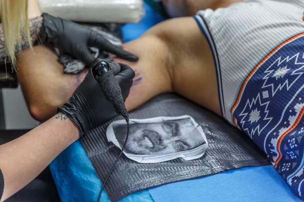 Egy tattooist nő vázlatok egy tetoválás a karján, egy fiú - Fotó, kép