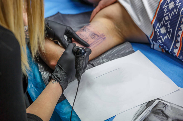 A tattoo artist woman is depicting a tattoo on the arm of a boy - Photo, Image