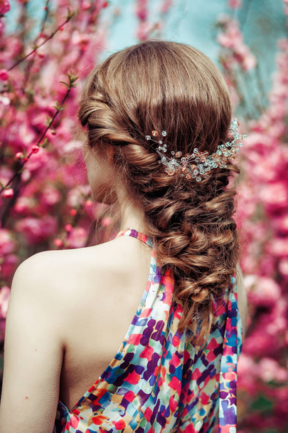 beautiful woman with decoration in her hair in the spring park with blossoming cherry trees - Valokuva, kuva