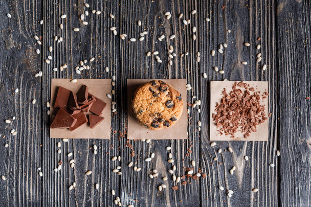 Пачка классического шоколадного печенья и шоколадных хлопьев на салфетке на деревенском тёмном столе. Вид сверху
. - Фото, изображение