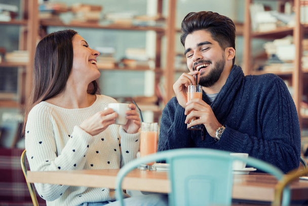 Молода пара сидить у кафе і сміється
 - Фото, зображення