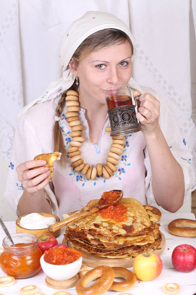 The girl at the festive table eating pancakes and drinking tea - Φωτογραφία, εικόνα